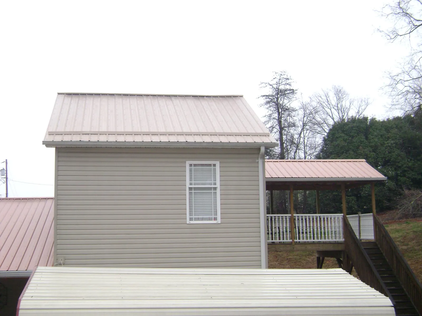 Tan metal roofs on a two story addition and attached porch, from a Roof Replacement job in Chatsworth